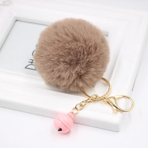 Detailed close-up of soft brown faux rabbit fur keychain with pink bell and golden clasp