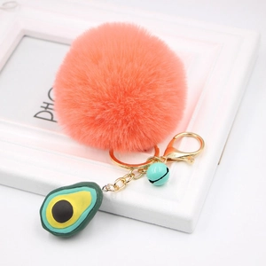 Detail of soft peach faux fur pompom with avocado pendant and blue bell key ring