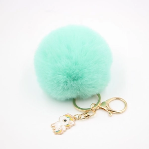 Détail d'un porte-clés pompon vert menthe avec fermoir doré et pendentif licorne coloré