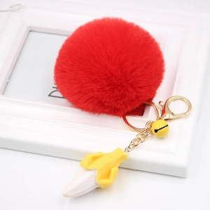 Detail of red faux fur pompom keychain with banana charm and gold metal lobster clasp