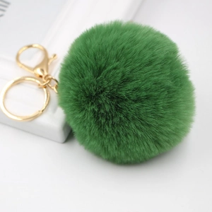 Detailed close-up of dark green faux fur pompom keychain with gold lobster clasp