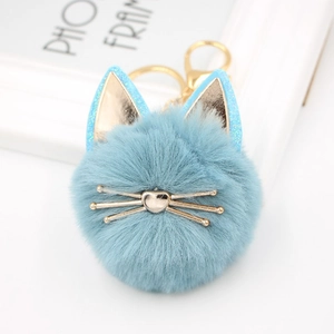 Close-up of light blue plush cat keychain with golden ears and metal whiskers