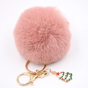 Détail d'un porte-clés pompon rose en peluche avec fermoir doré et charme d'arbre de Noël