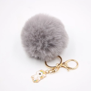 Vue détaillée du porte-clés pompon gris avec breloque licorne en métal doré