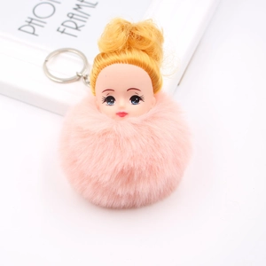 Détail de porte-clés pompon rose en fausse fourrure avec tête de poupée mignonne