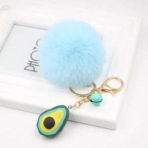 Detail of blue plush pompom keychain with resin avocado charm and green metal bell