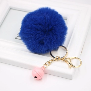 Close-up of royal blue faux rabbit fur pompom with a pink bell and gold metal clasp