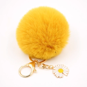 Détail du porte-clés pompon jaune en peluche avec anneau doré et breloque marguerite
