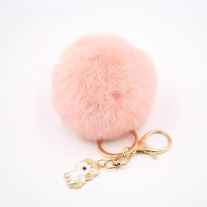 Détail d'un porte-clés pompon rose en fausse fourrure avec un pendentif licorne arc-en-ciel