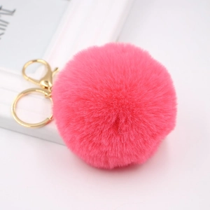 Detailed close-up of pink fluffy faux rabbit fur pom pom with gold lobster clasp and ring