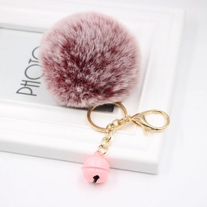Detail of burgundy plush pompom keychain with gold alloy ring and pink small bell