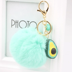 Detailed macro view of mint green plush pompom keychain with cute avocado resin charm