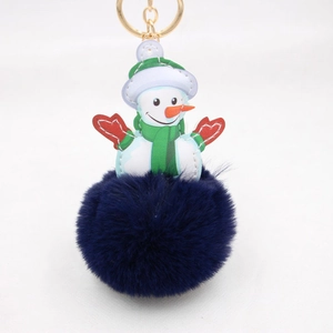 Close-up of fluffy blue pompom and snowman leather charm with gold keychain clasp
