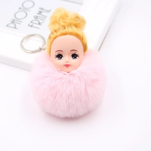 Détail d'un porte-clés pompon en fausse fourrure rose avec tête de poupée et anneau
