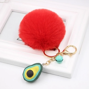 Detail of red plush faux fur pompom keychain with avocado pendant and blue bell charms