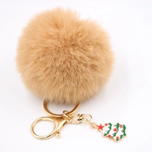 Détail du porte-clés pompon en fausse fourrure beige avec fermoir doré et charme de Noël