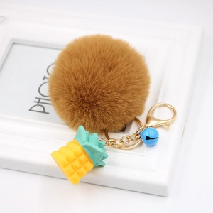 Detail of a brown fluffy faux fur keychain with yellow pineapple charm and gold hardware