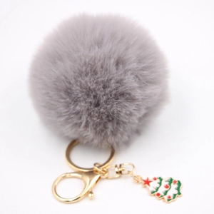 Détail du pompon en peluche grise avec un charm de sapin de Noël et un fermoir doré brillant