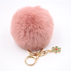 Détail d'un porte-clés pompon rose avec breloque flocon de neige dorée et strass rouge