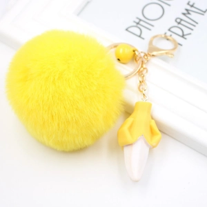 Plush yellow pompom keychain with a peeled banana charm and golden alloy metal hardware