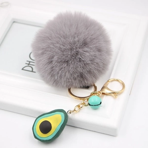 Detail of grey faux fur pom pom keychain with avocado charm and golden clasp hardware