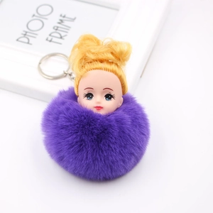 Détail d'un porte-clés pompon violet en fausse fourrure avec tête de poupée et anneau argenté