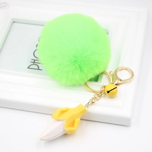Macro view of fluorescent green pompom keychain with yellow resin banana pendant and gold bell