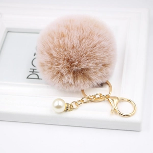 Detailed view of fluffy beige faux fur keychain with gold ring and pearl charm decoration