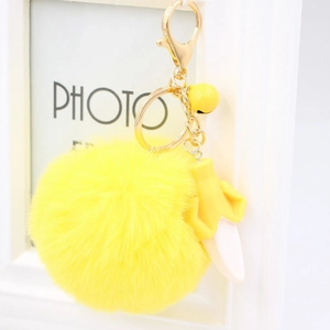 Detail of fluffy yellow plush pom pom keychain with banana charm and golden spring clip