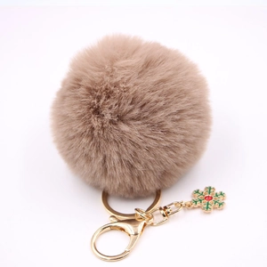 Détail d'un porte-clés pompon marron clair avec breloque flocon de neige dorée et fermoir