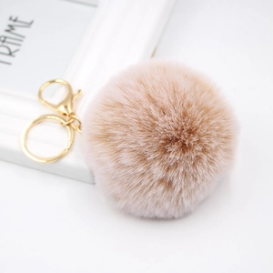 Detail of soft faux fur pompom keychain in nude pink with golden ring and lobster clasp