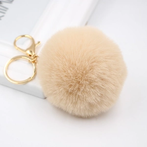 Close-up of beige 8cm faux fur pompom keychain with golden lobster clasp and metal ring