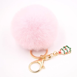 Détail d'un porte-clés pompon en fausse fourrure rose avec breloque sapin de Noël et métal doré