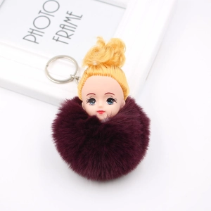 Détail d'un porte-clés poupée mignonne avec pompon en fausse fourrure bordeaux et anneau