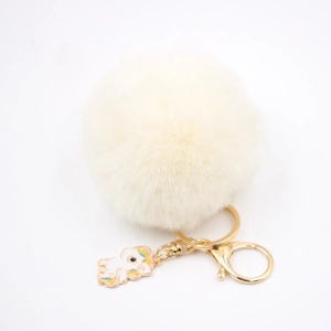 Détail du porte-clés licorne avec pompon en fausse fourrure crème et attache dorée
