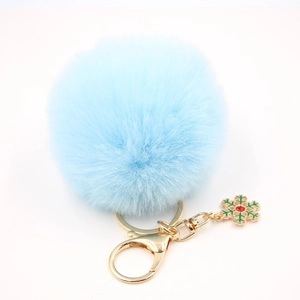Détail d'un porte-clés pompon bleu clair avec pendentif flocon de neige festif