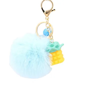 Light blue pompom keychain with a pineapple pendant and gold metal hardware for bags