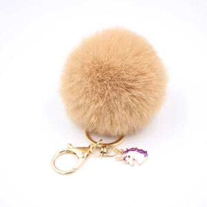 Detailed close-up of khaki faux fur pompom keychain with golden unicorn charm