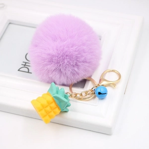 Purple fluffy pom pom keychain with a golden resin pineapple charm and blue bell