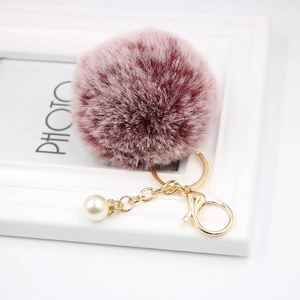 Close-up of wine red faux fur pompom keychain with gold chain and pearl accent