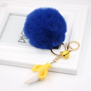 Detailed view of royal blue faux fur pompom with yellow banana charm and golden metal hardware