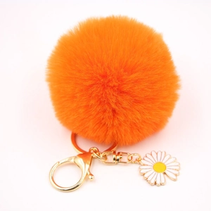 Détail d'un porte-clés pompon orange doux avec fermoir doré et breloque marguerite