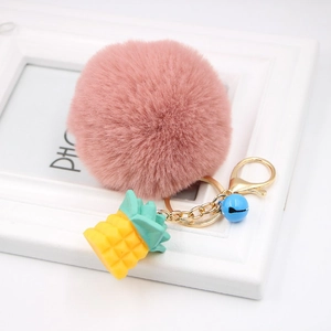 Detail of pink faux fur keychain with a yellow pineapple charm and gold lobster clasp