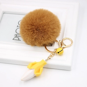 Detailed close-up of brown faux fur pompom keychain with yellow resin banana and bell