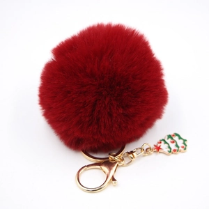 Détail du porte-clés pompon en fausse fourrure bordeaux avec anneau doré et sapin de Noël