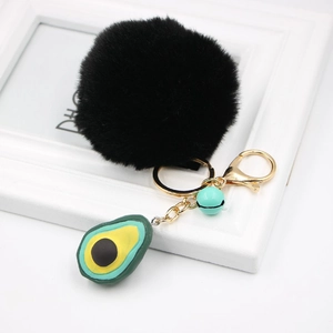 Detail of avocado keychain featuring a black faux fur pom pom and gold-tone lobster clasp