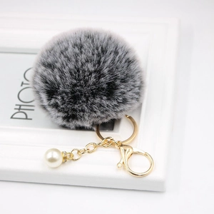 Detailed view of bicolor faux fur pompom keychain with golden lobster clasp and pearl