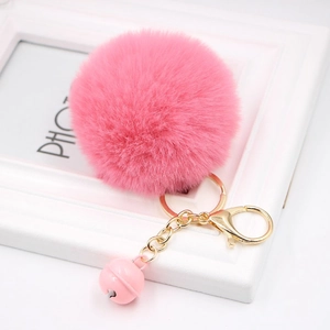 Close-up of pink faux rabbit fur pompom keychain with golden clasp and matching bell