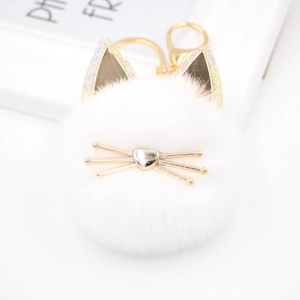 Detailed view of white plush cat keychain with golden heart nose and whiskers on white decor