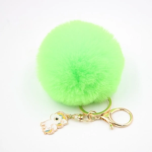 Détail du porte-clés pompon vert néon en fausse fourrure avec breloque licorne en or